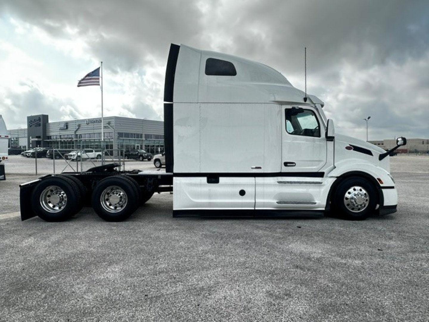 Peterbilt 579 semi-truck side view showing sleeper cab, long hood, white paint.