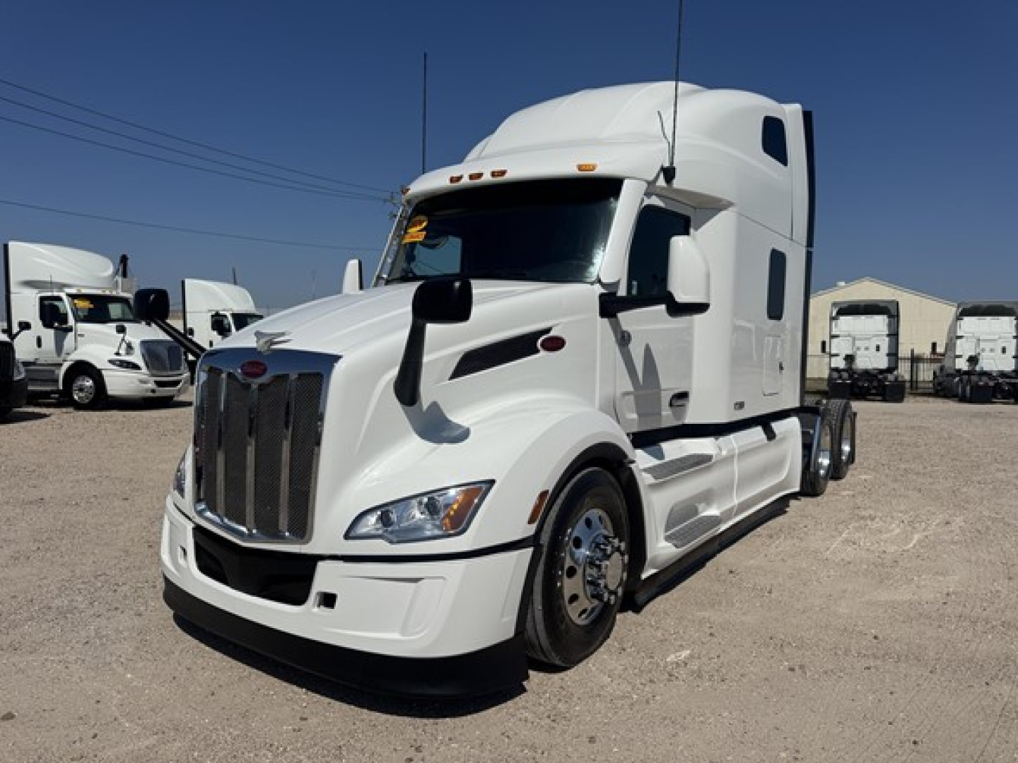 Peterbilt 579 conventional sleeper truck in white, front 3/4 view with chrome grille and aerodynamic mirrors.