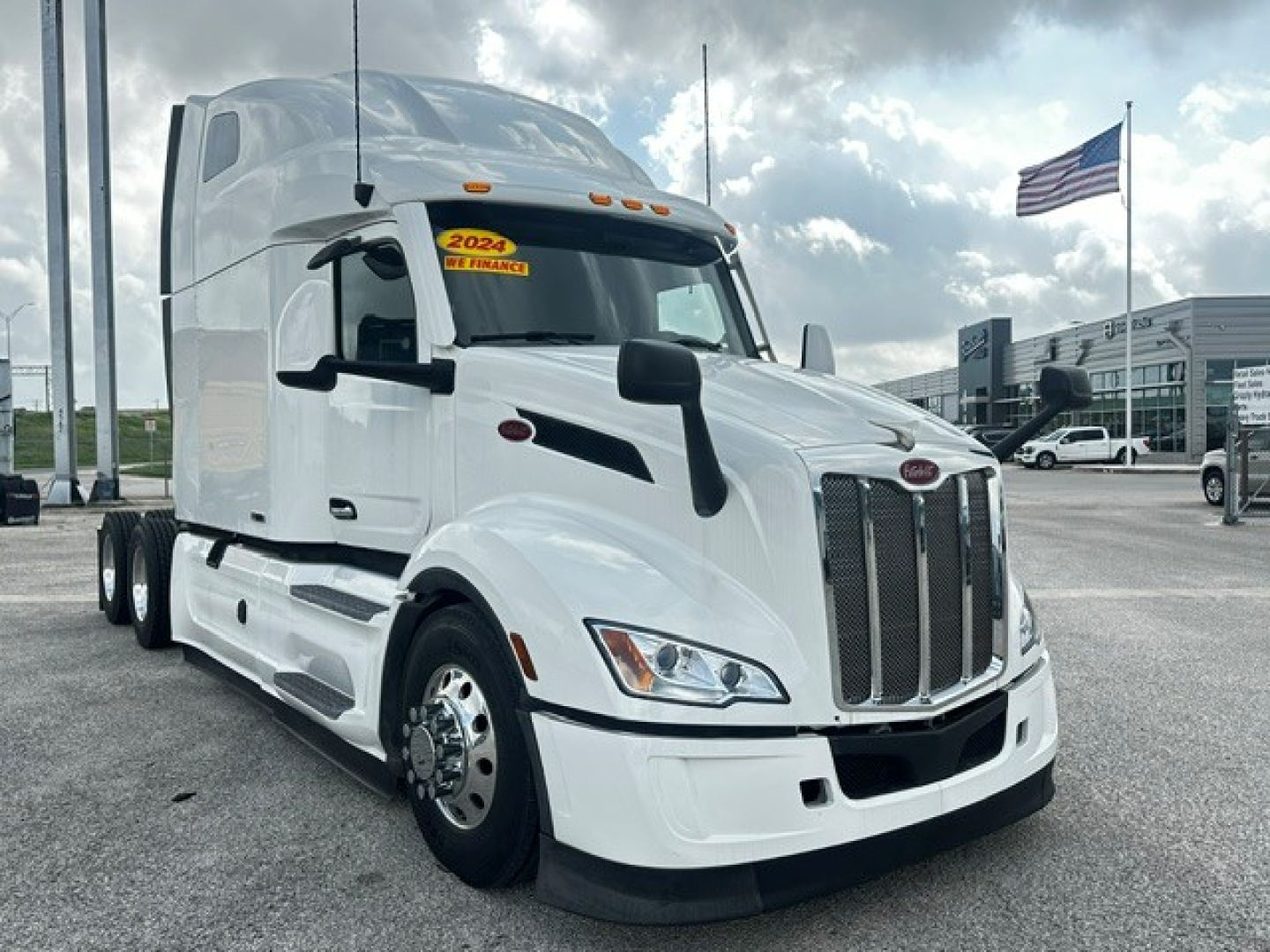 Peterbilt 579 tractor in white, front three-quarter view showing grille, headlights, and sleeper cab with 2024 sticker on windshield.