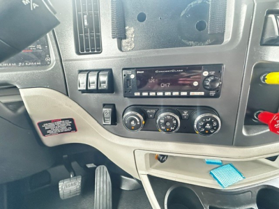 Peterbilt 579 truck cabin dash showing factory radio and climate controls with CH7 display, various gauges, and a blue tag visible.