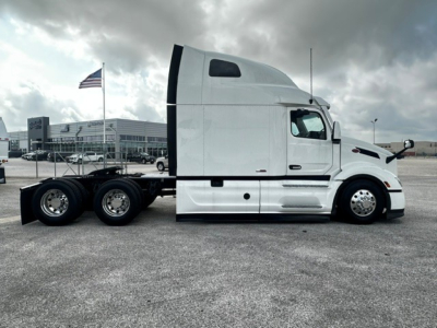Peterbilt 579 semi-truck side view showing sleeper cab, long hood, white paint.
