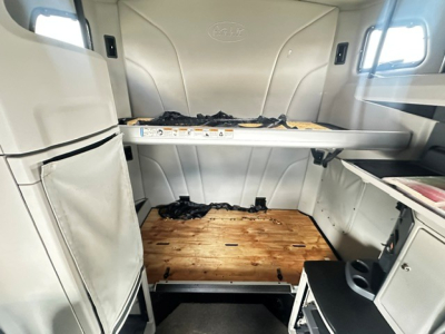 Peterbilt 579 sleeper cab interior showing lower bunk bed area with wood floor and storage cabinets.