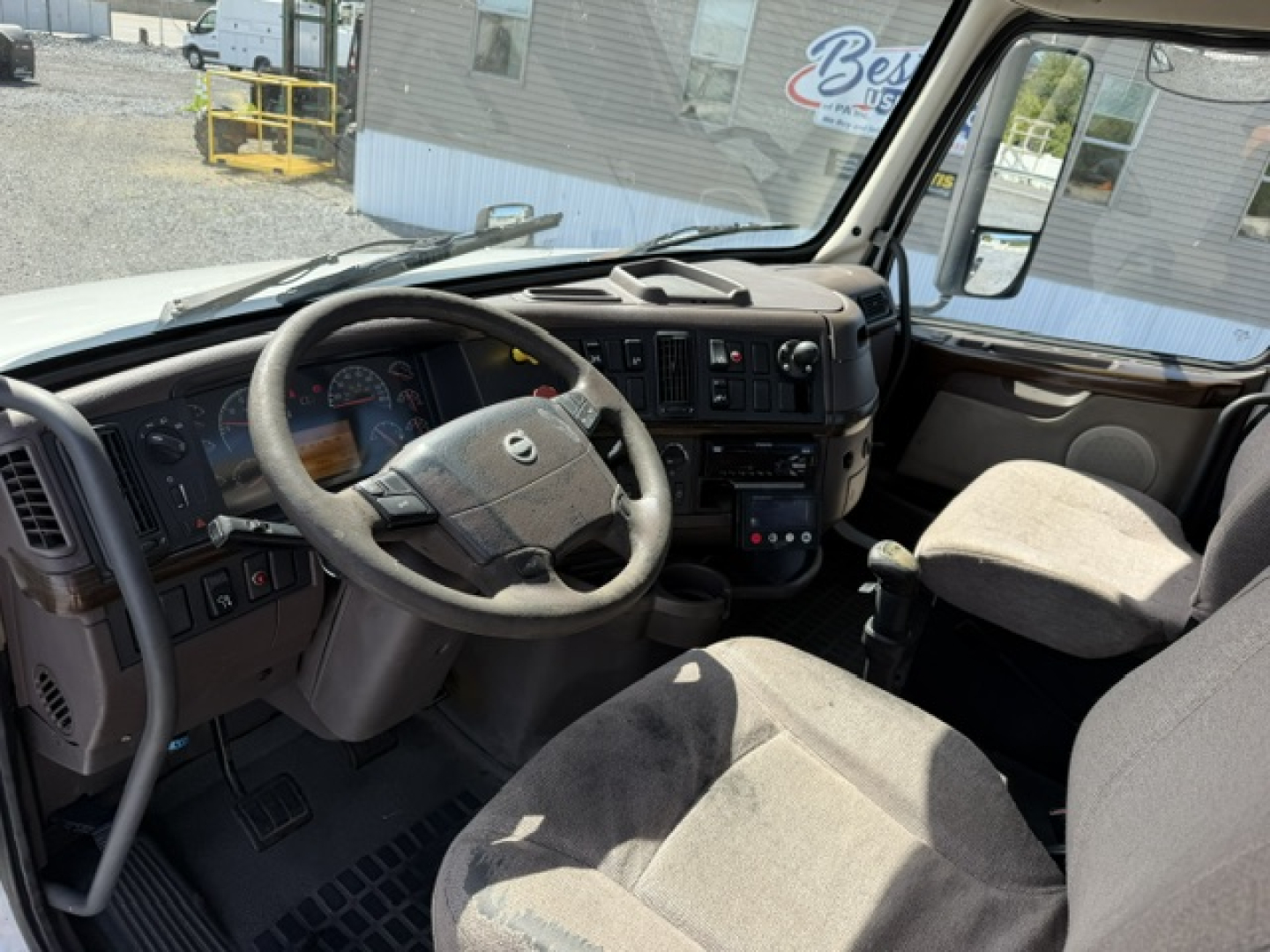 Volvo VNL64T300 cab interior showing steering wheel, dashboard, and driver seat from passenger side.
