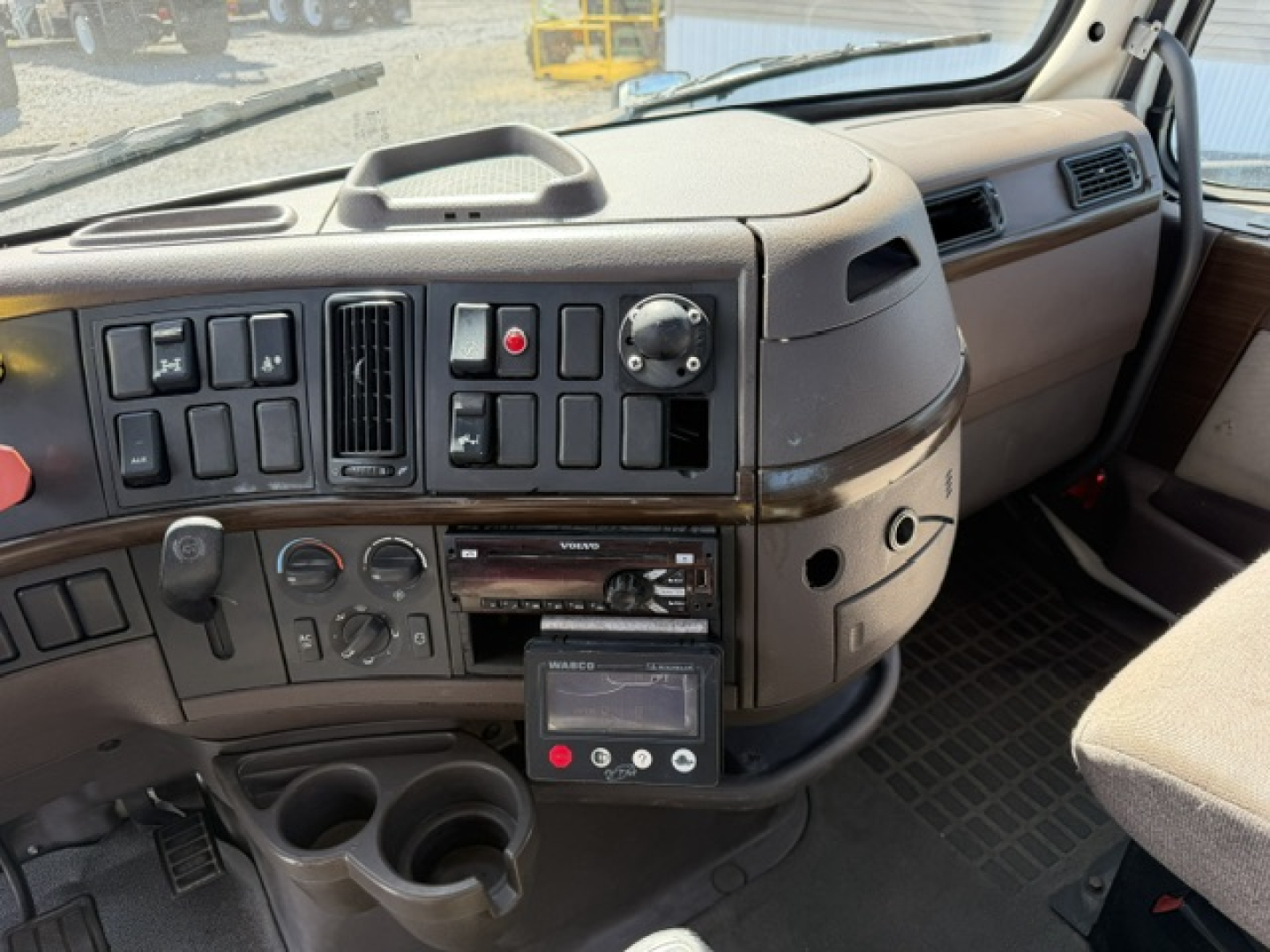 Volvo VNL64T300 truck interior dashboard with instrument panel, control switches, radio, and cup holders.
