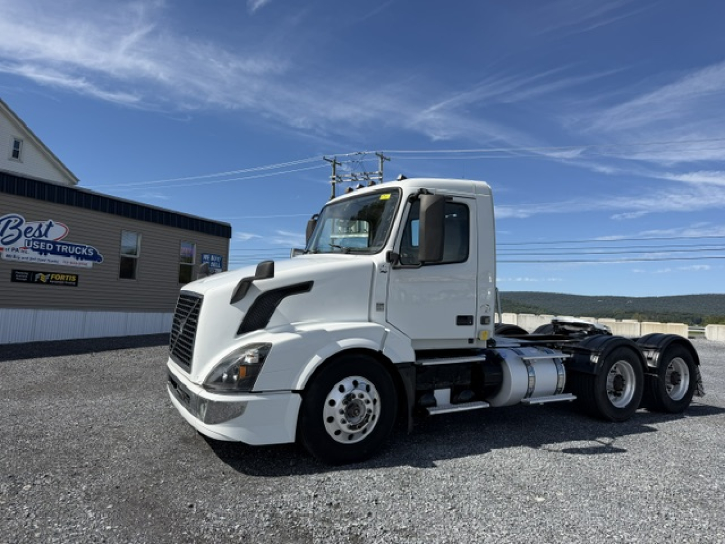 Volvo VNL64T300 day cab tractor shows front and side view with white paint and fuel tanks.