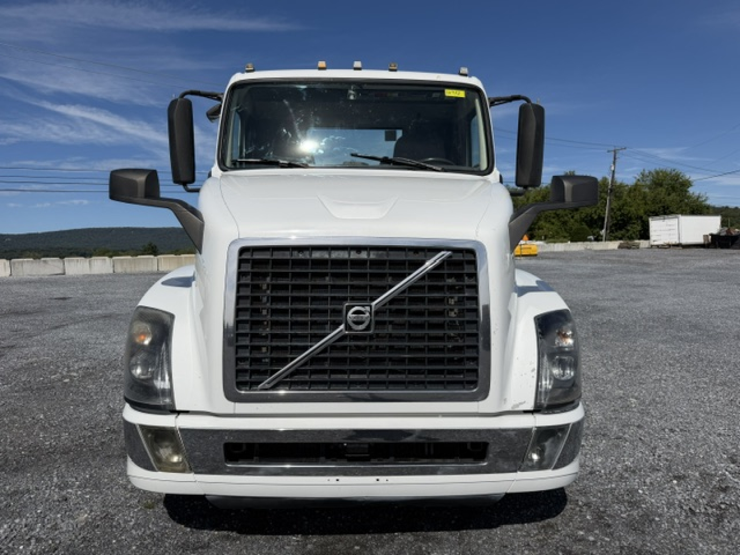Front view of a white 2016 Volvo VNL64T300 truck showing large black grille with Volvo emblem, rectangular headlights, mirrors, and bumper.