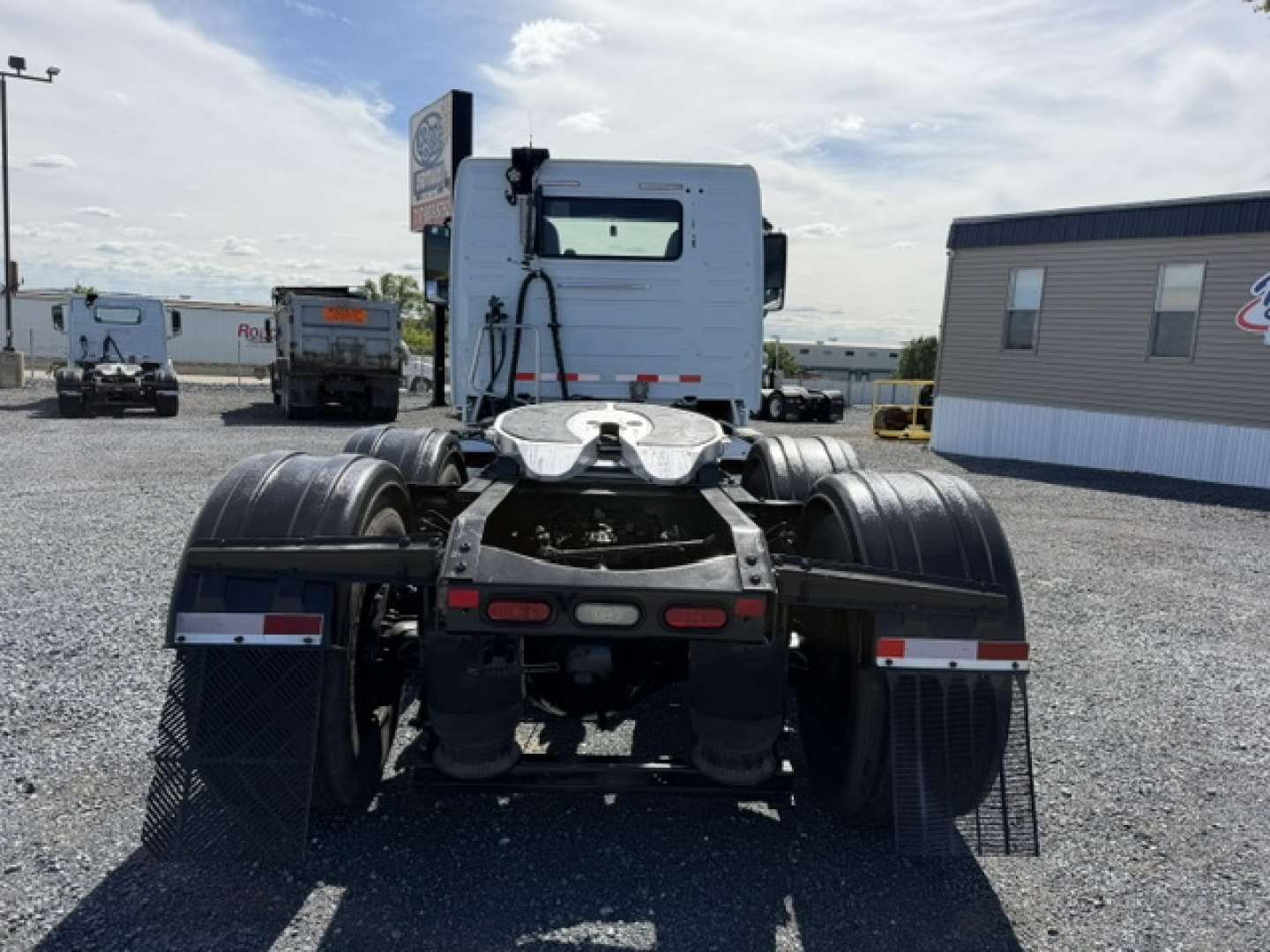 Rear view of a 2016 Volvo VNL64T300 truck tractor chassis with fifth wheel, dual rear axles, and mud flaps.
