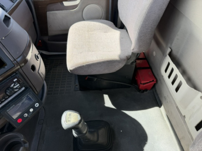 Volvo VNL64T300 cab interior showing manual shift knob, driver seat, dashboard, and passenger side with storage under seat.