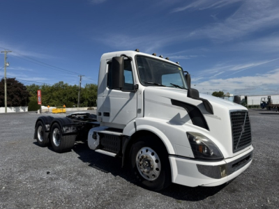 Volvo VNL64T300 day cab truck side view showing front grille, headlights, and wheel with dual rear axles.