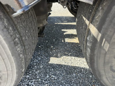 Volvo VNL64T300 truck undercarriage showing rear dual tires and gap between axles. Visible tread and gravel surface.