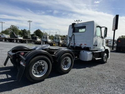 Truck tractor side view showing sleeper cab, dual rear axles, Volvo VNL64T300 series with white exterior and exposed chassis.
