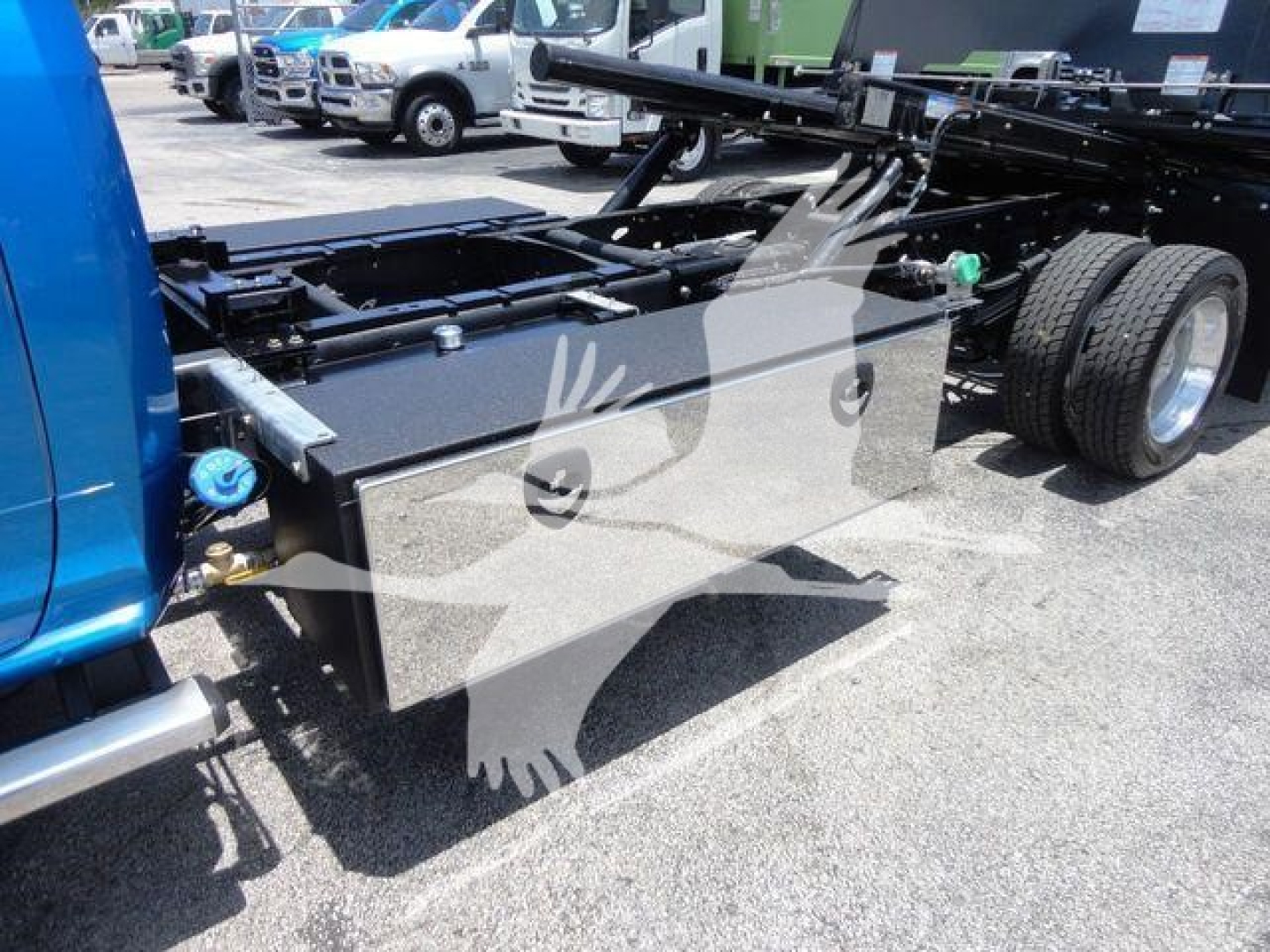 Truck chassis with a large aluminum tool/storage box mounted on the frame, rear wheels visible, RAM 5500 chassis cab in view, rollback setup.