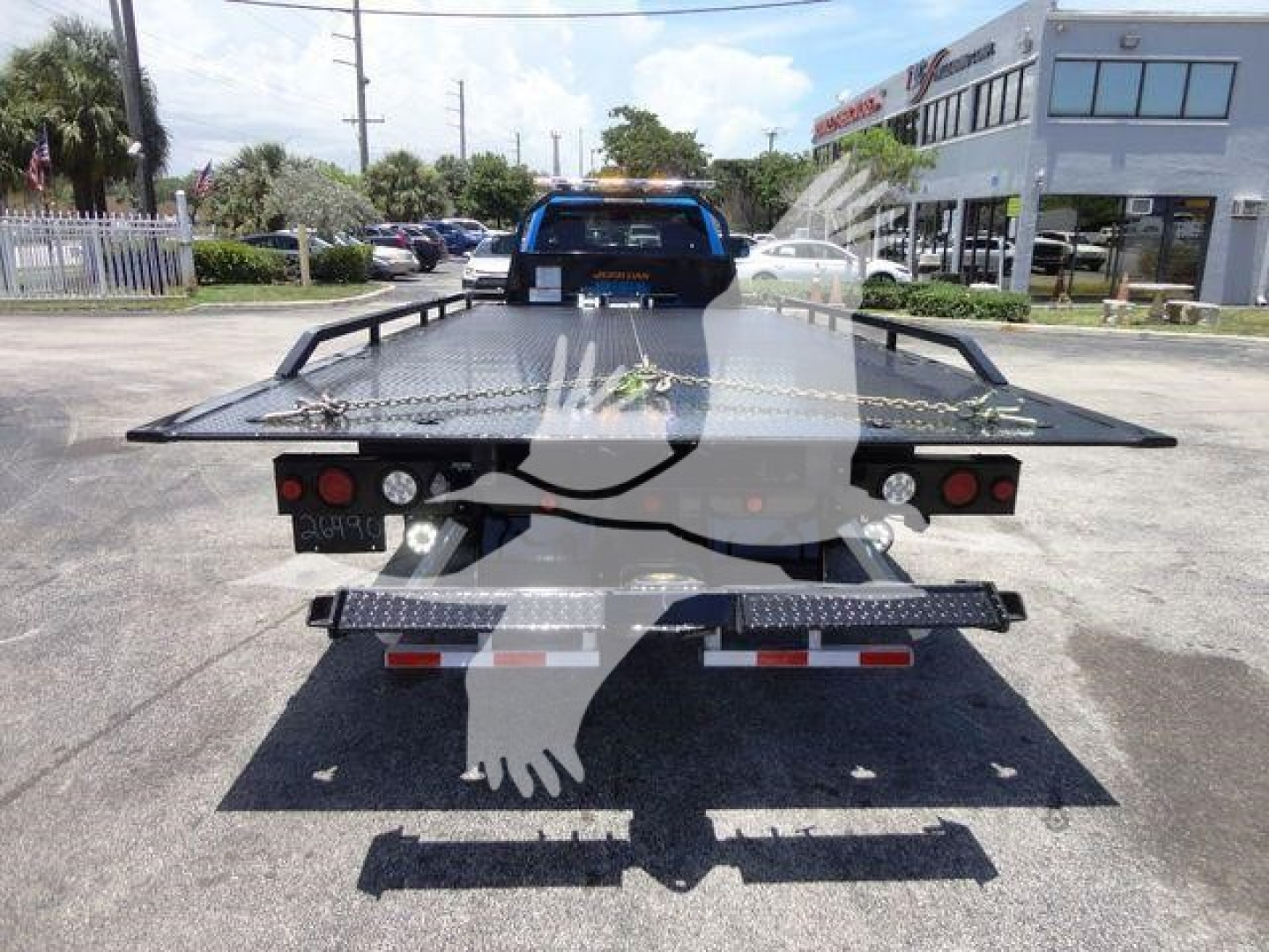 Ram 5500 rollback tow truck rear view showing flatbed with caution markings and taillights.