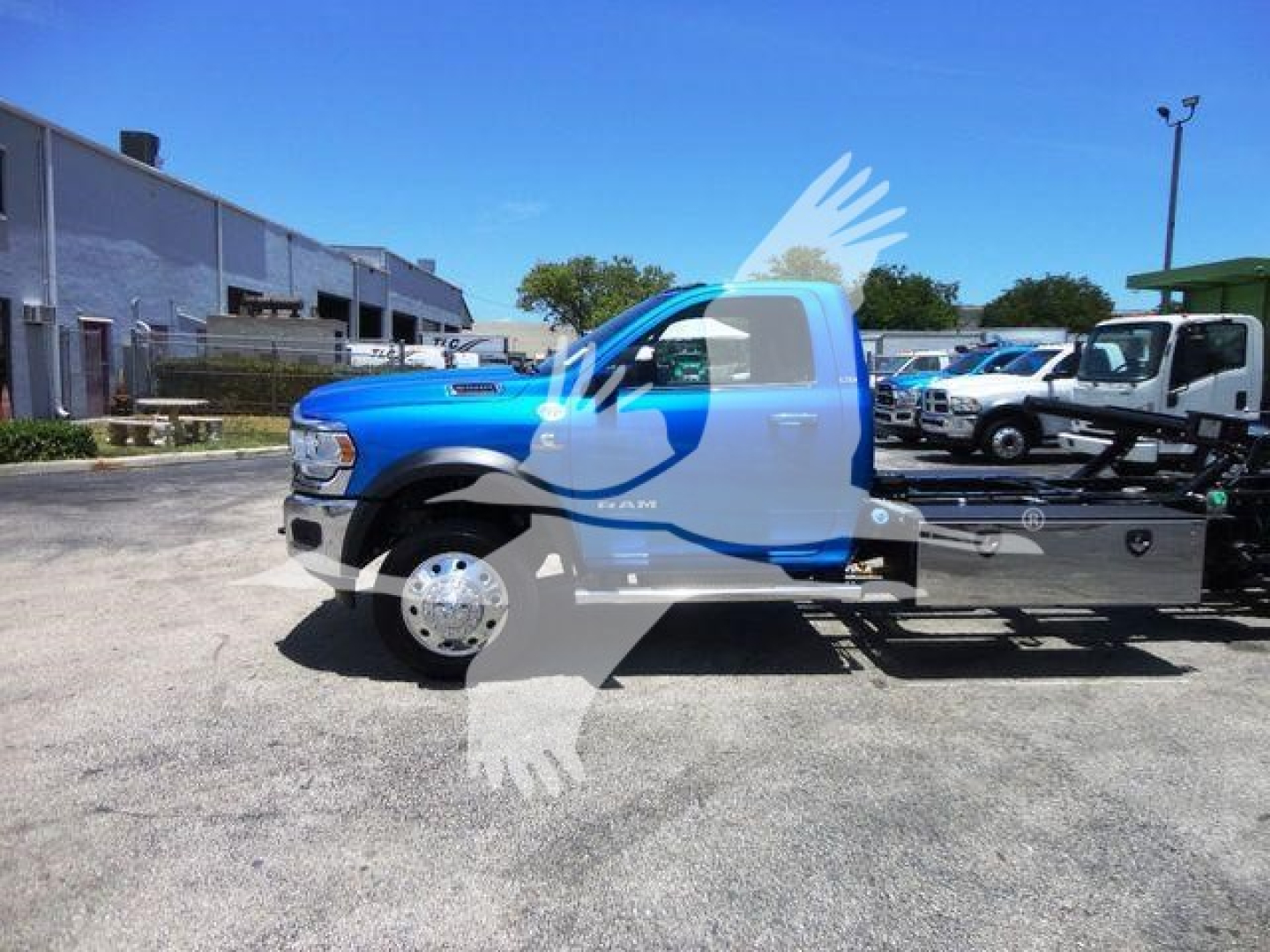 Blue Ram 5500 rollback truck side view showing front grille, cab, and flatbed on a dealership lot