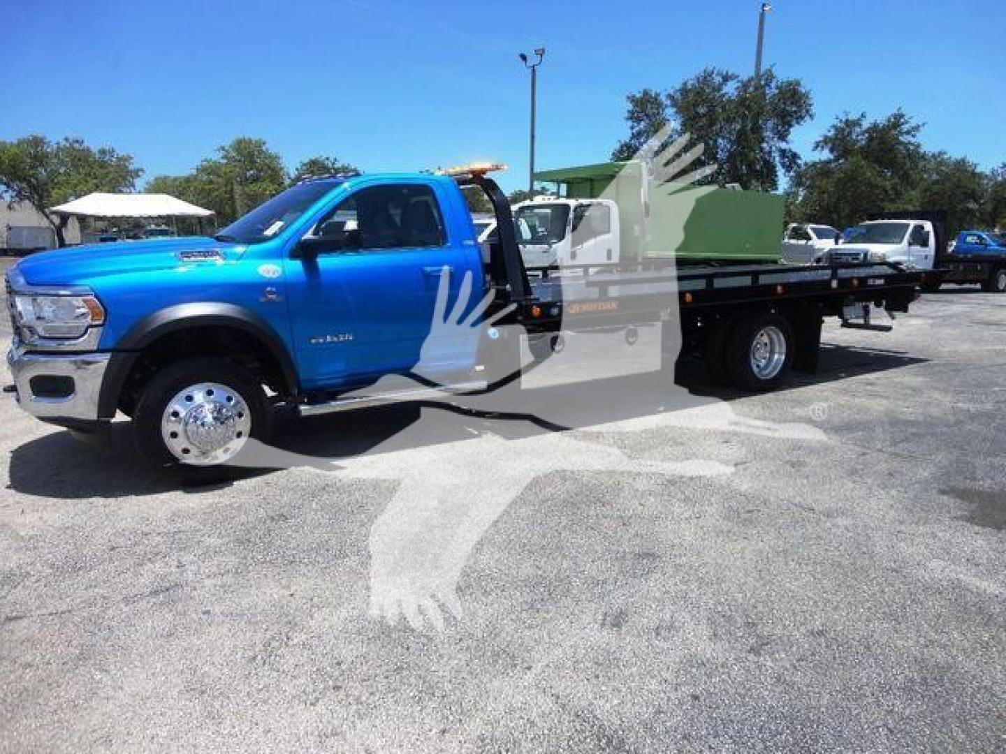 Ram 5500 truck with blue cab and rollback flatbed, side view showing extended cab and dual rear wheels.