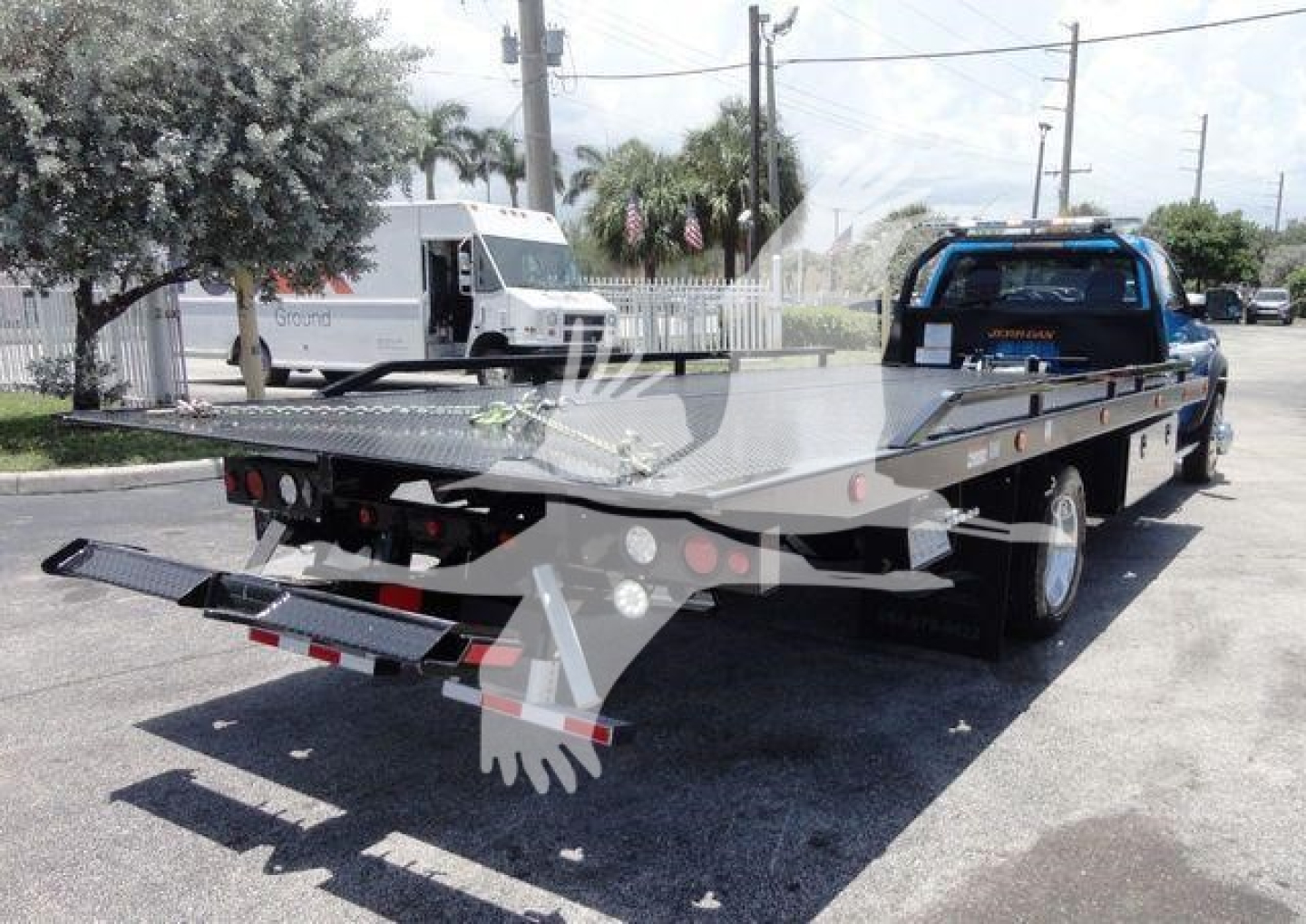 Ram 5500 rollback tow truck flatbed with rear ramps and hydraulic system visible.