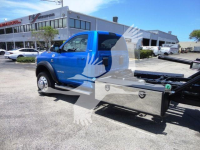 Blue 2024 Ram 5500 cab with rollback equipment and metal flatbed in a dealership lot