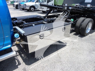 Truck chassis with a large aluminum tool/storage box mounted on the frame, rear wheels visible, RAM 5500 chassis cab in view, rollback setup.