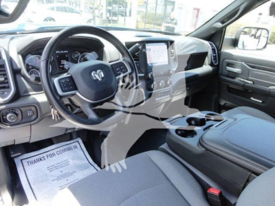 Ram pickup interior showing steering wheel with ram logo, center console, and dashboard; dashboard screen and controls visible.