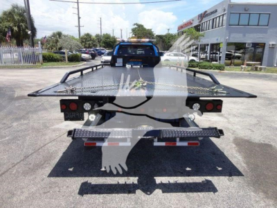 Ram 5500 rollback tow truck rear view showing flatbed with caution markings and taillights.