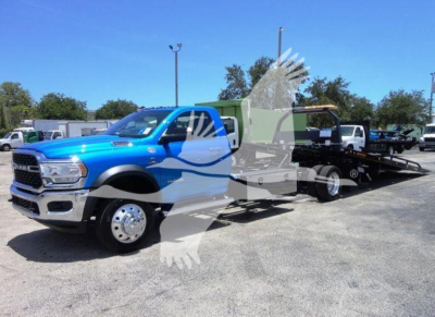 2024 Ram 5500 SLT with rollback tow truck configuration showing blue cab and black flatbed in showroom lot.