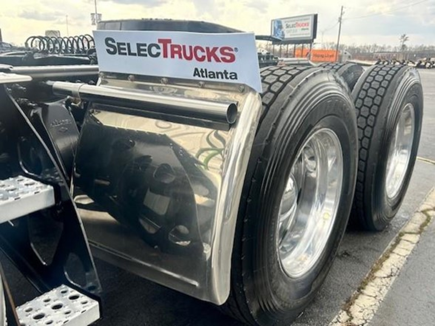 Truck rear view showing dual rear wheels and fuel tank on Freightliner Cascadia 126 sleeper cab chassis with SelecTrucks Atlanta sign.
