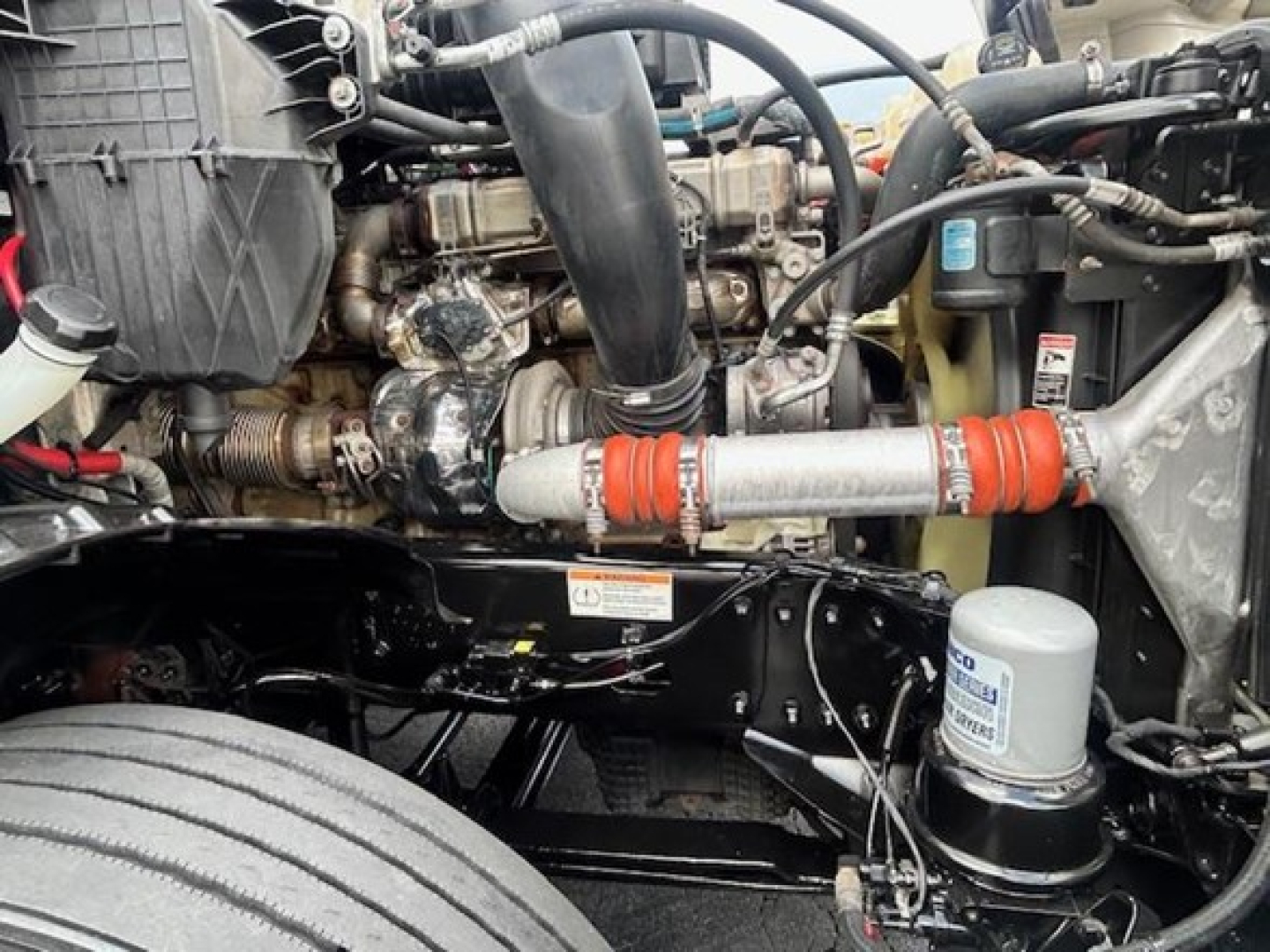 Freightliner Cascadia 126 engine bay showing engine components, hoses, coolant reservoir, and filter canister.