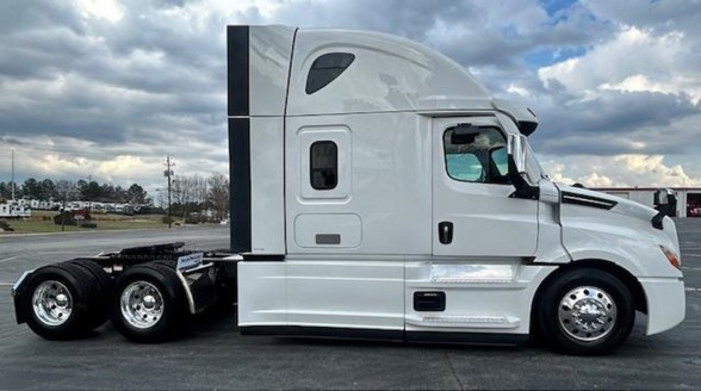 Truck side view of a white Freightliner Cascadia 126 tractor with sleeper cab and dual rear axles.