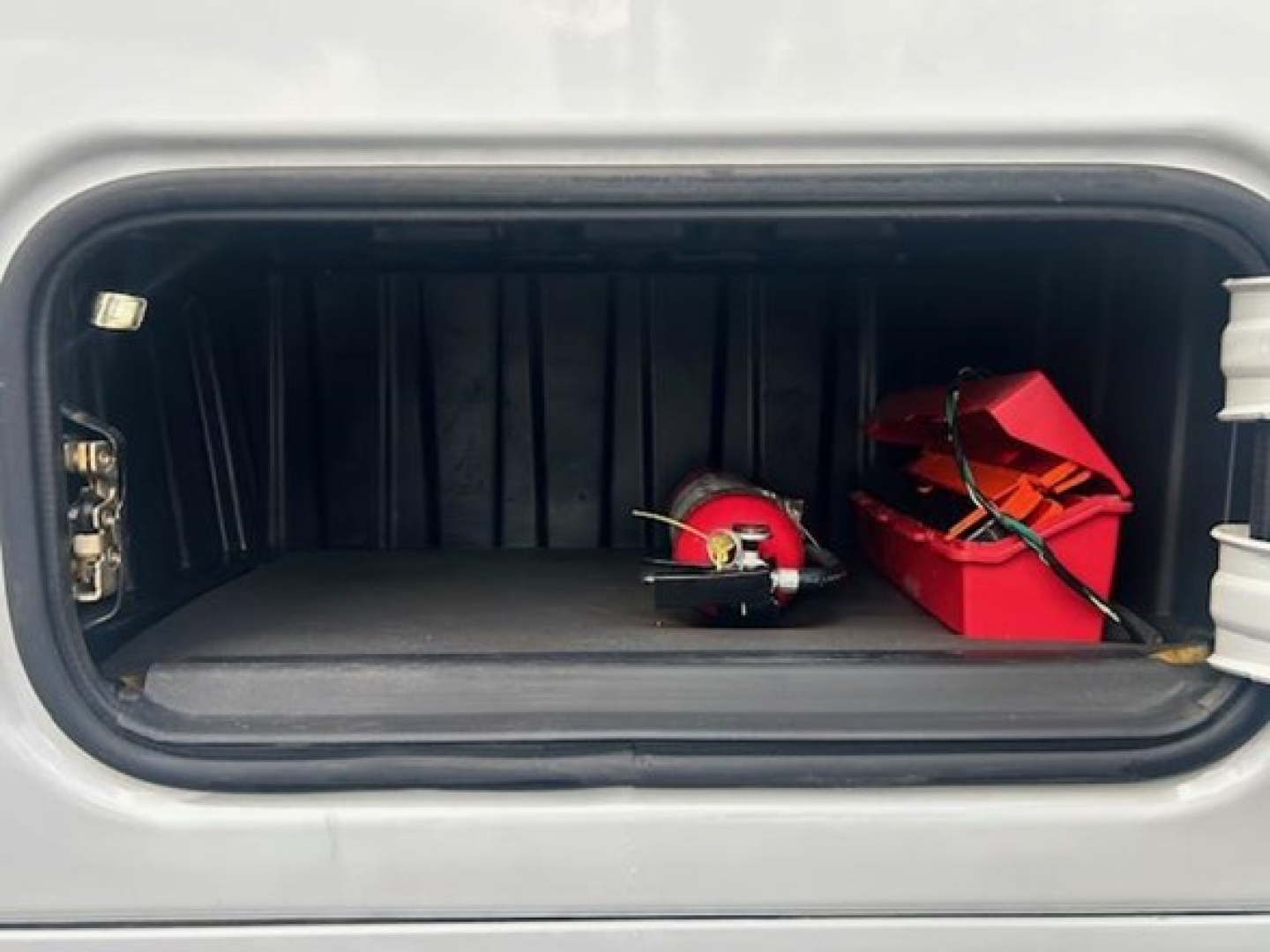 Cargo area of a Freightliner Cascadia 126 sleeper cab showing storage box and tools in the front storage compartment.