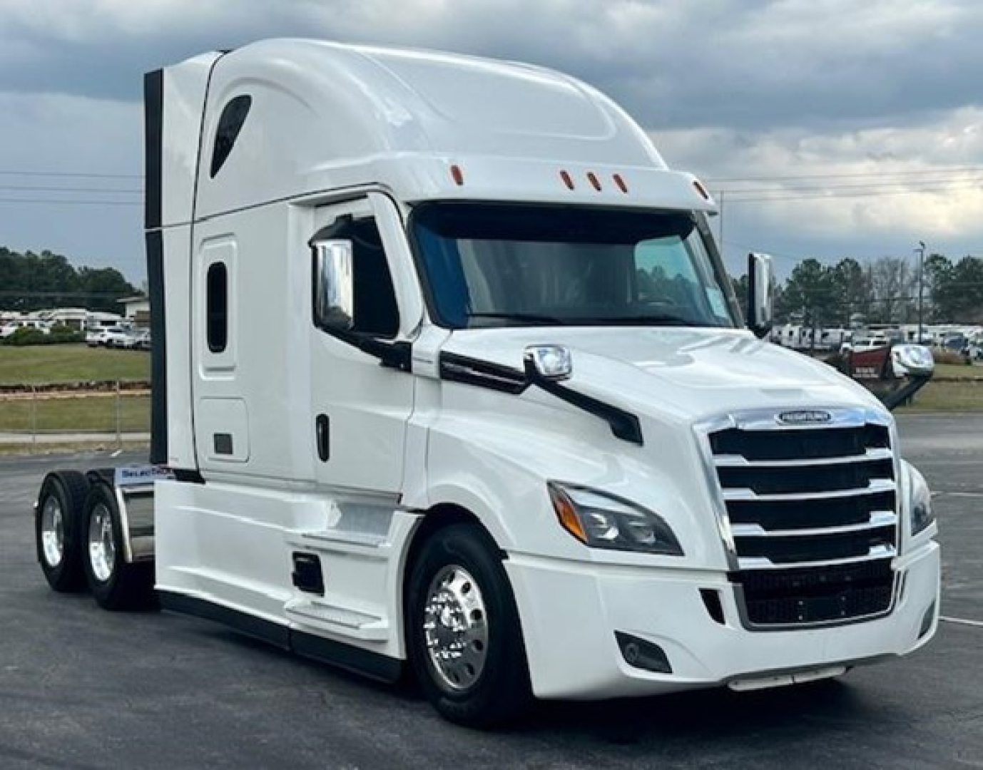 Truck cab and front section of a white Freightliner Cascadia 126 tractor with sleeper cabin, chrome grille, and dual rear wheels.