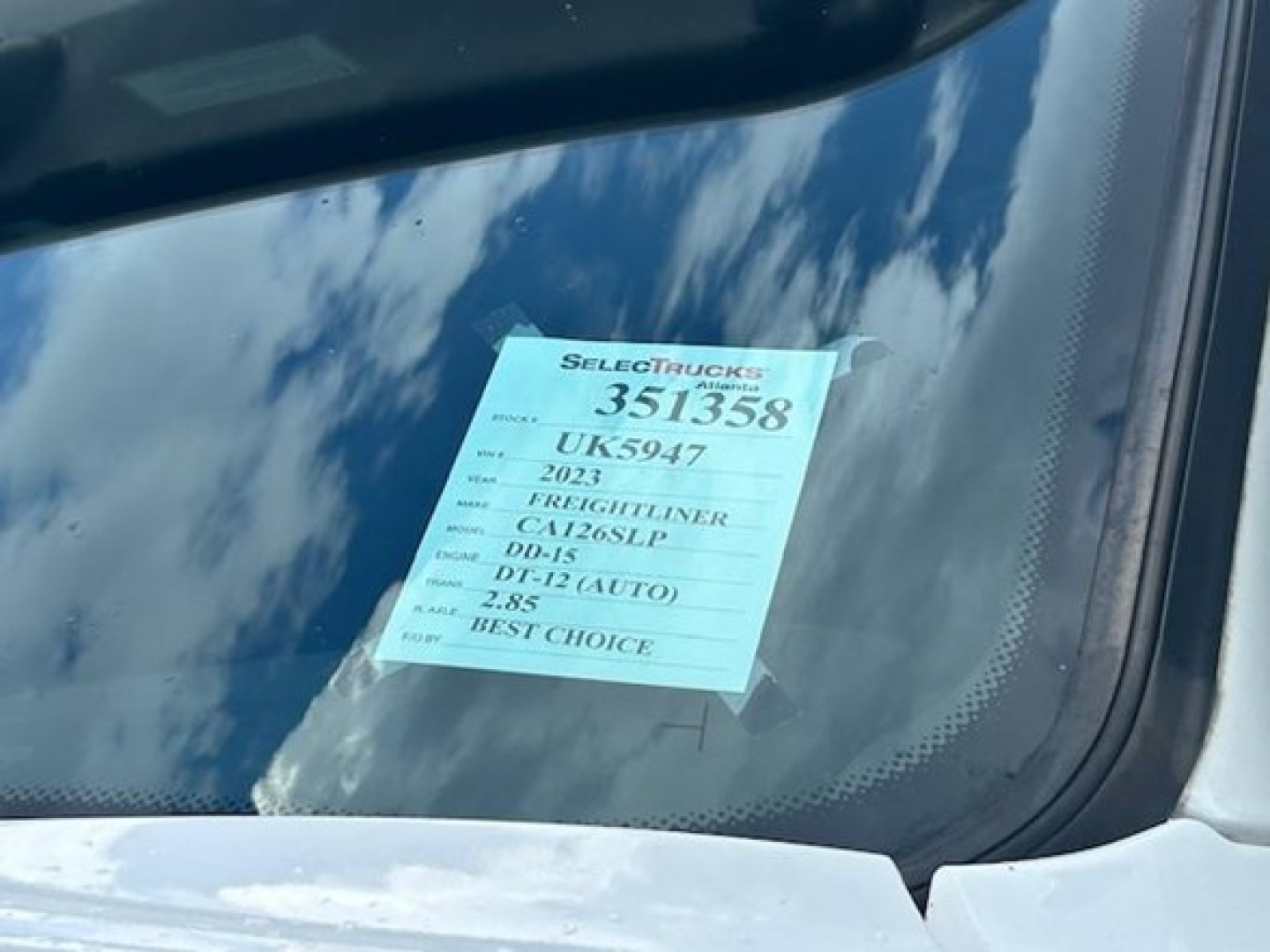 Truck windshield with a blue auction-style tag showing stock number 351358 and VIN details visible through the glass.