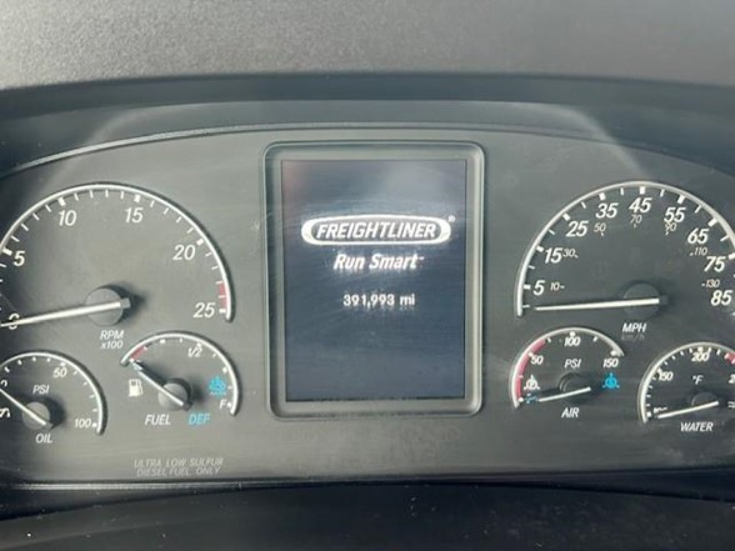 Dashboard of a Freightliner Cascadia showing central screen with Freightliner logo and mileage 391,993 mi; gauges on left and right with RPM, oil, fuel, DEF, air, water, and mph scales.
