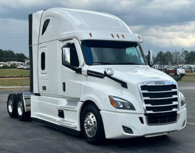 Truck cab and front section of a white Freightliner Cascadia 126 tractor with sleeper cabin, chrome grille, and dual rear wheels.