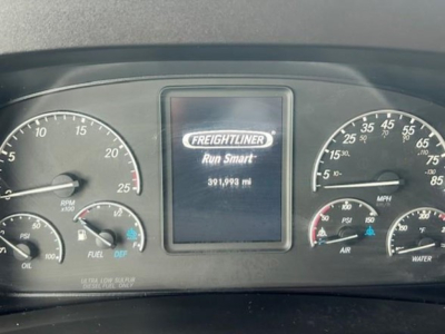 Dashboard of a Freightliner Cascadia showing central screen with Freightliner logo and mileage 391,993 mi; gauges on left and right with RPM, oil, fuel, DEF, air, water, and mph scales.