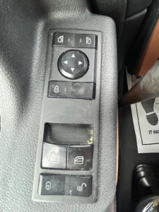Truck interior control panel with window/mirror adjust buttons and lock switches visible.