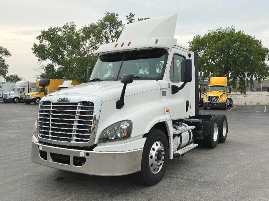 Truck cab and chassis showing Freightliner Cascadia125 daycab with white exterior, large chrome grille, hood, dual rear axles, and integrated sleeper area.