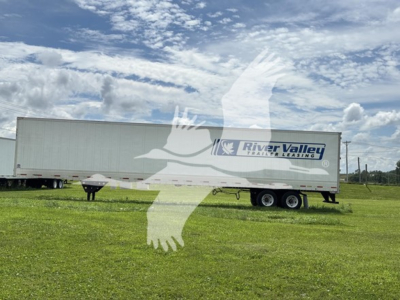 Trailer showing River Valley Trailers Leasing logo on side with dual-axle on grassy lot.