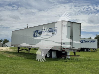 Utility trailer 4000D-X with River Valley Trailer Leasing logo on side, side view showing rear doors, in a grassy lot.