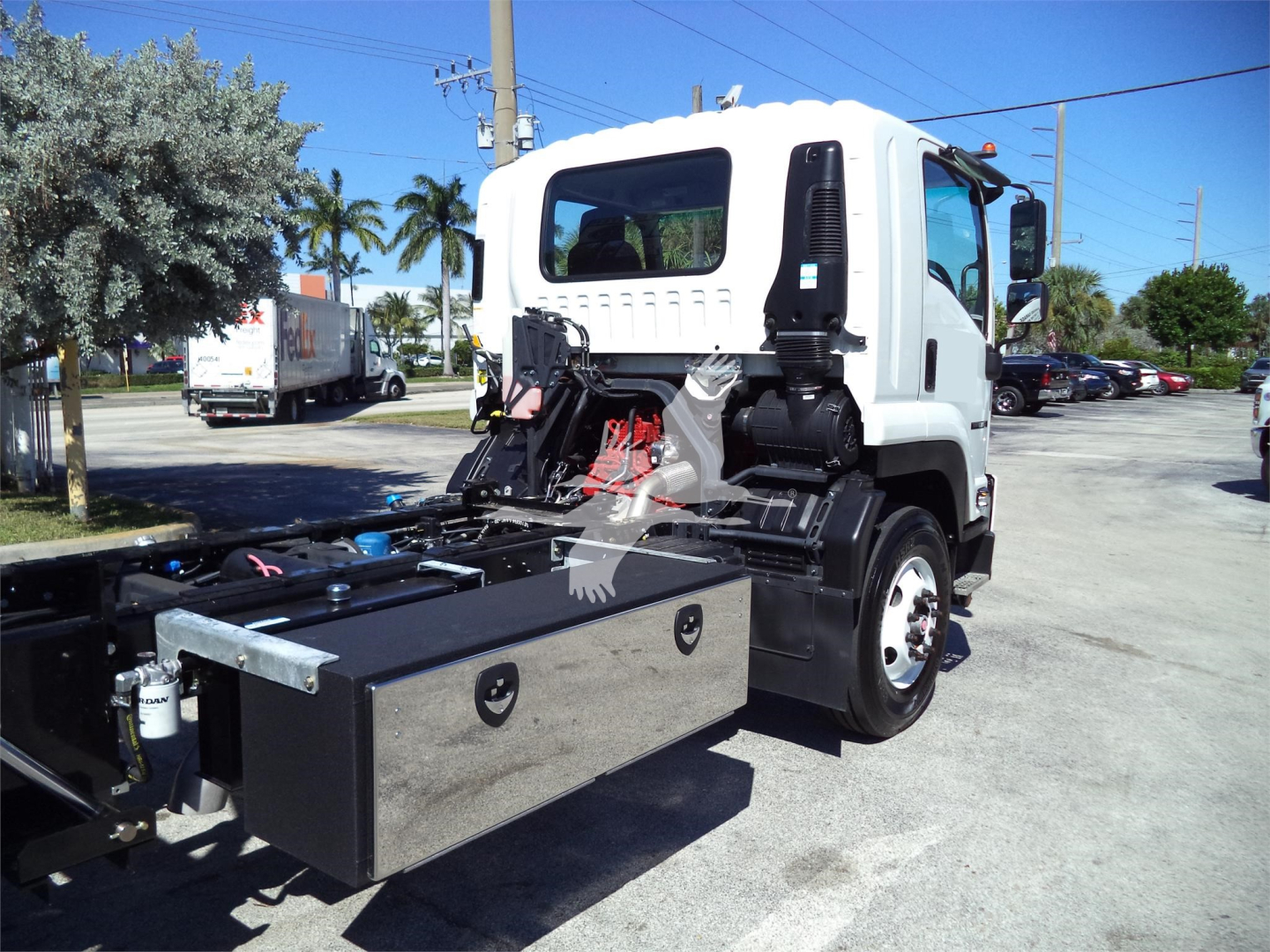 Isuzu FRR rollback tow truck cab and chassis showing hydraulic system and rectangular tool/storage box on side, white cab with black accents.