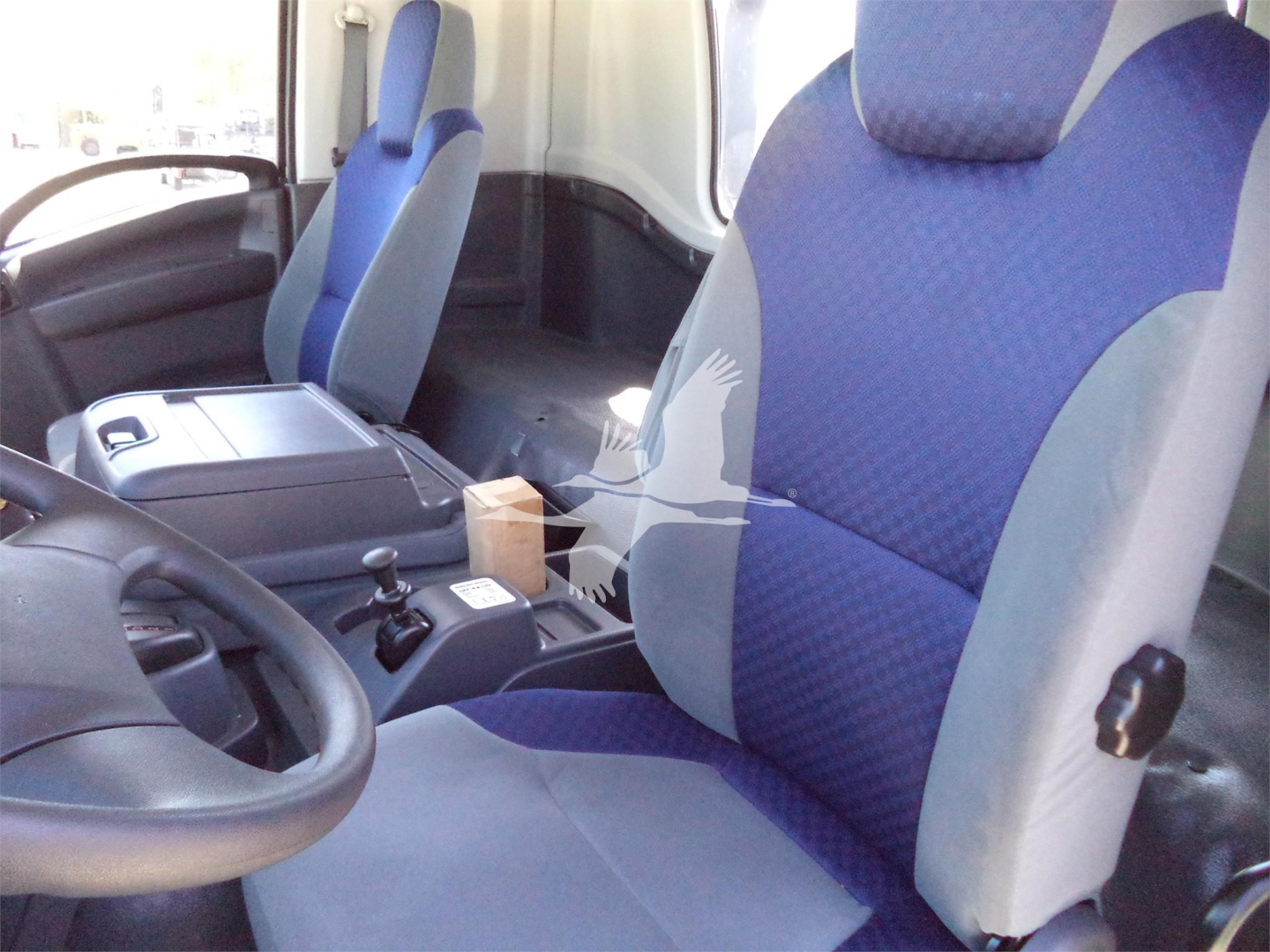 Isuzu FTR cab interior showing blue fabric seats, steering wheel, center console with gear shifter, and dashboard.