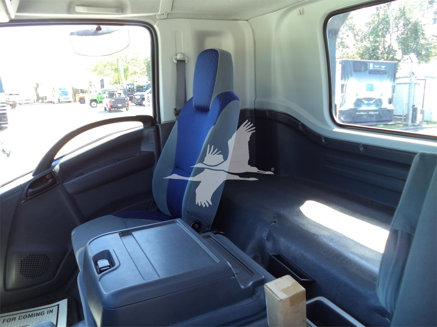 Truck cab interior showing blue and gray seat, center console, side window, and cargo area.