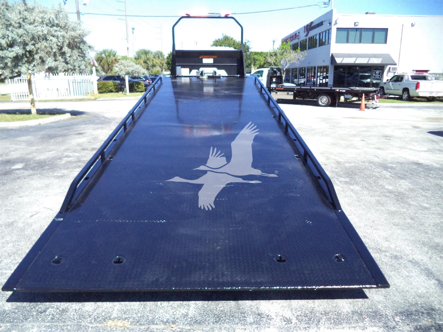 Isuzu FTR rollback truck bed with extended flatbed and ramp end, showing a large Isuzu logo on the metal surface.
