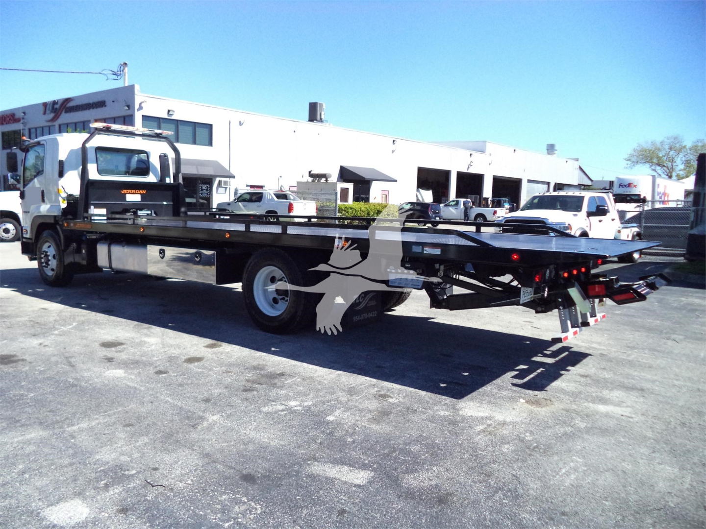 Isuzu FTR rollback tow truck chassis with flatbed and dual rear ramps visible.