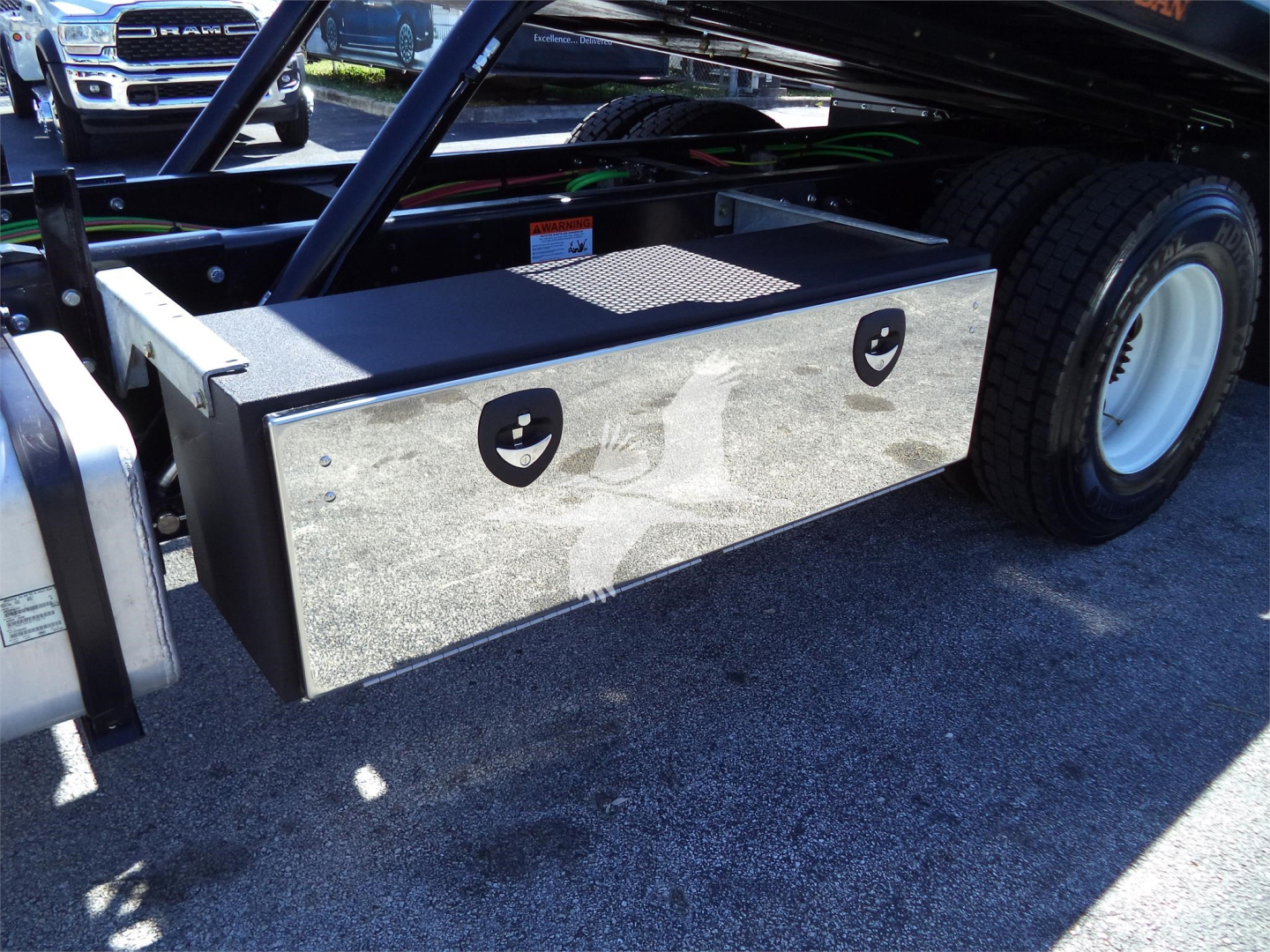 Isuzu FTR rollback truck showing a rectangular metal toolbox mounted near the rear wheel.