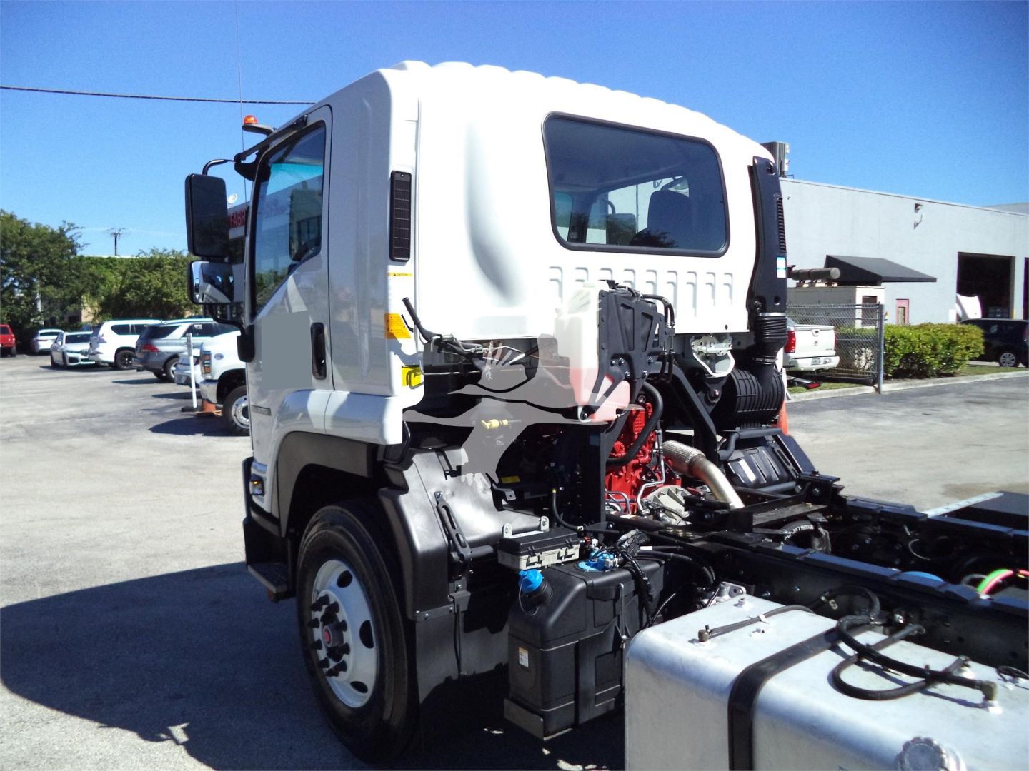 Isuzu FTR cab truck side view showing engine bay components and chassis with hoses, battery, and hydraulic lines.