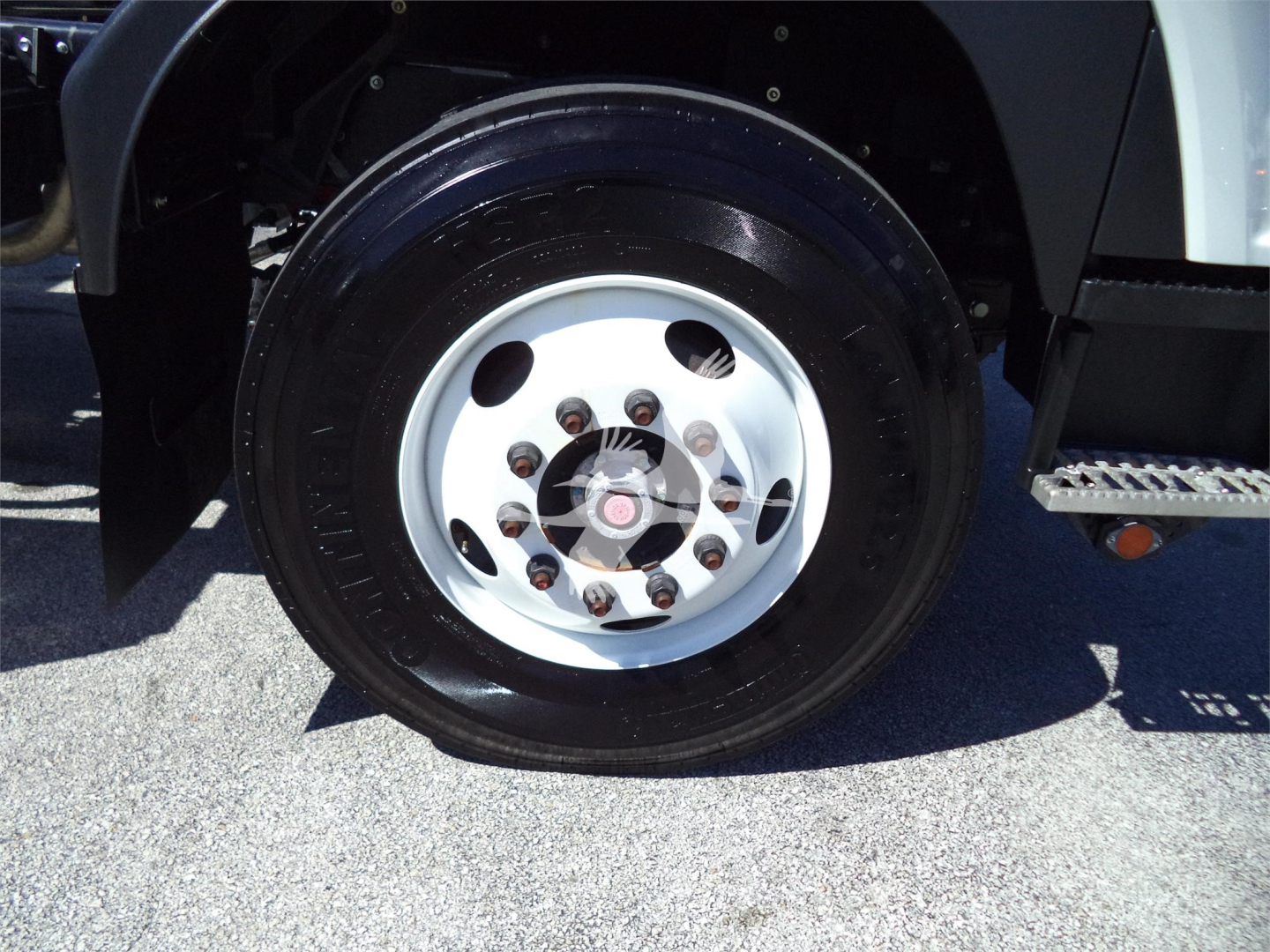 Isuzu FTR wheel and tire close-up showing steel wheel with lug nuts and hub, part of rollback truck.