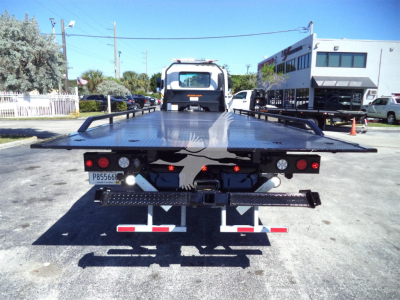 Flatbed tow truck bed of a 2025 Isuzu FTR rollback with rear lights, license plate P85666, and equipment racks on the sides.