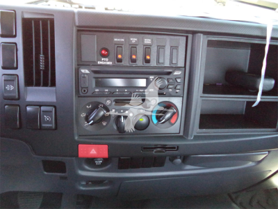 Isuzu FTR dashboard/controls panel with climate knobs, buttons, and media unit visible in the cab interior.