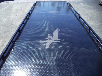 Isuzu rollback bed or trailer deck with diamond plate pattern and a white bird silhouette logo near center.