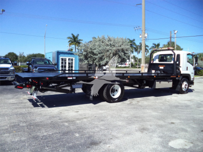 Isuzu rollback tow truck/flatbed with long industrial flatbed and two-tone cab in a dealership lot.